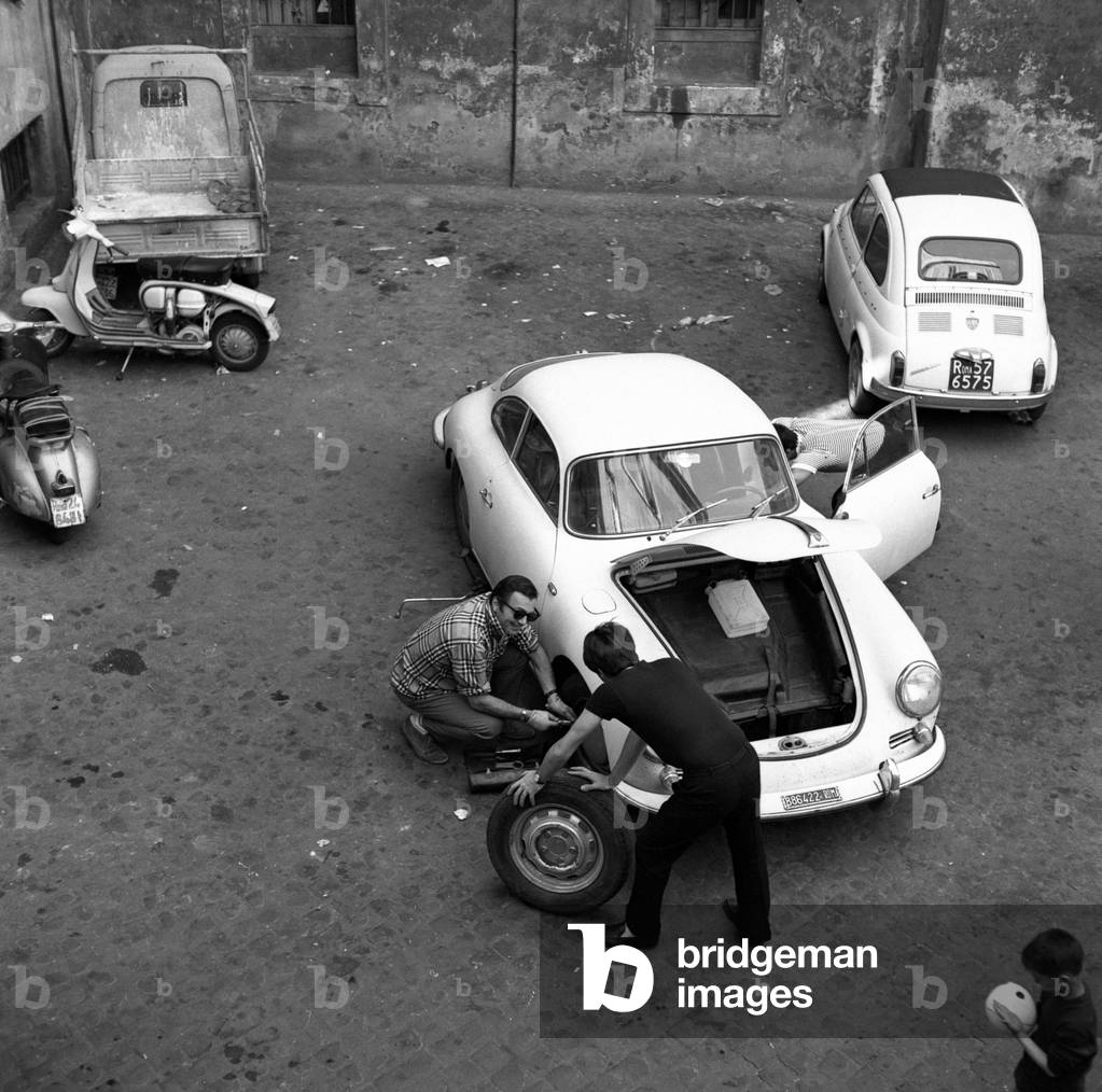 Three men changing car wheels, Italy
