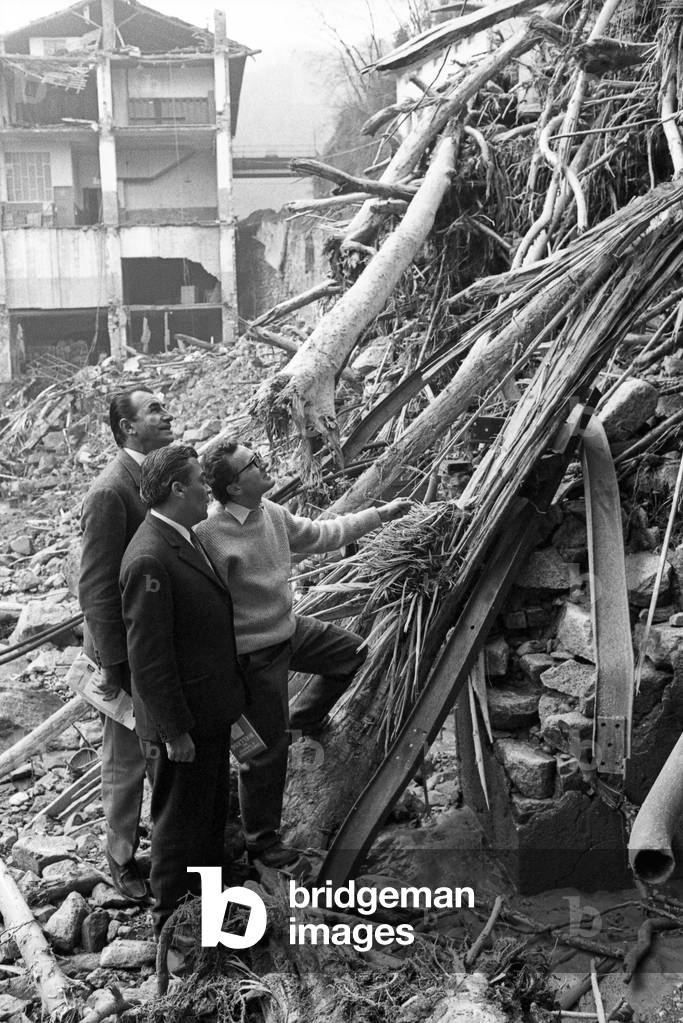 Some men looking at the rubbles left by the flood in the district of Biella, Italy, 1968 (b/w photo)