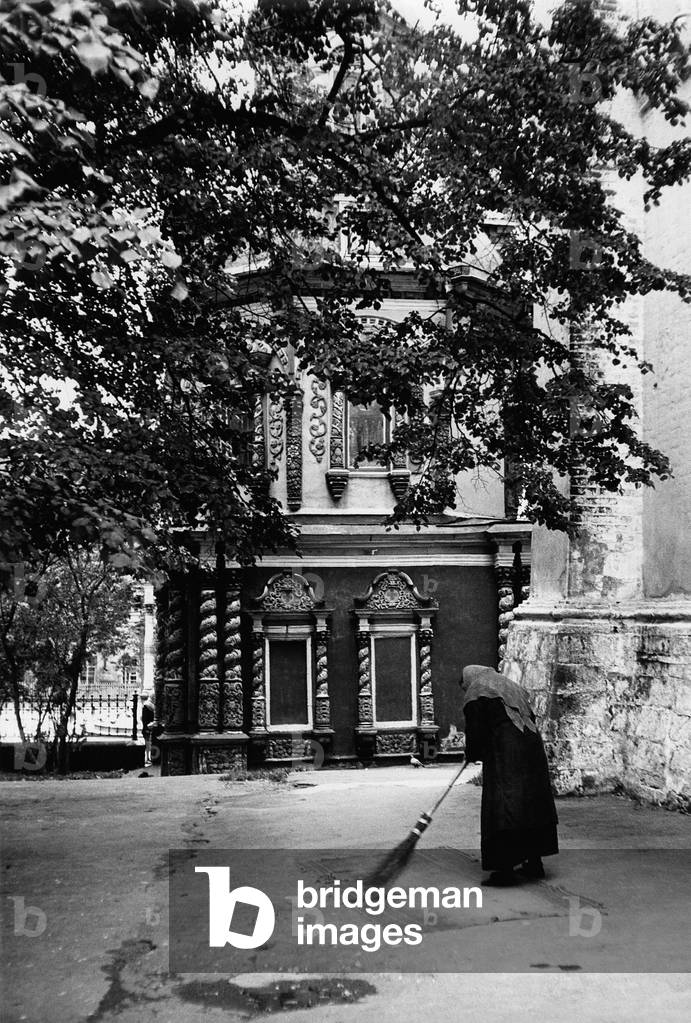 An attendant is cleaning a carpet in the little court next to Assumption Cathedral in Zagorsk, Zagorsk, Russia, 1964