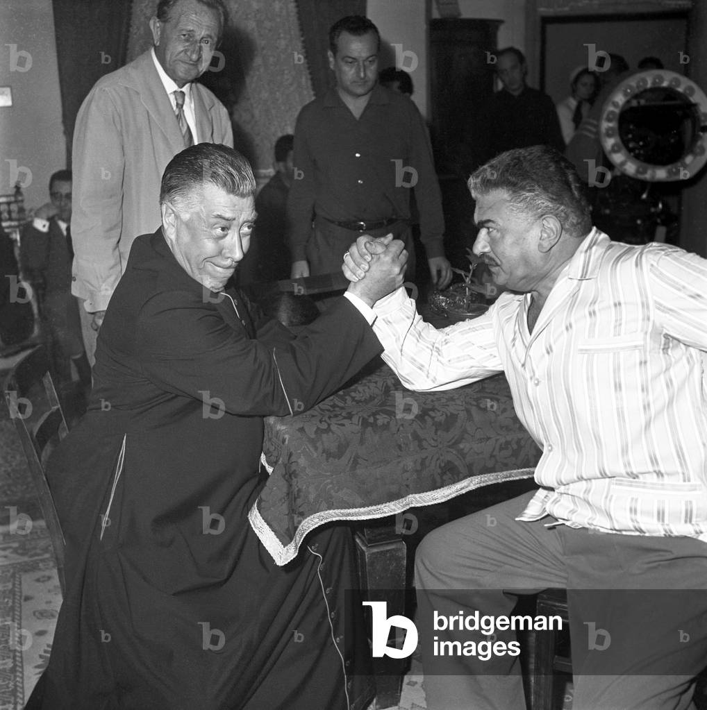 Italian actors Fernandel and Gino Cervi arm wrestling on the set, Italy, 1961 (b/w photo)