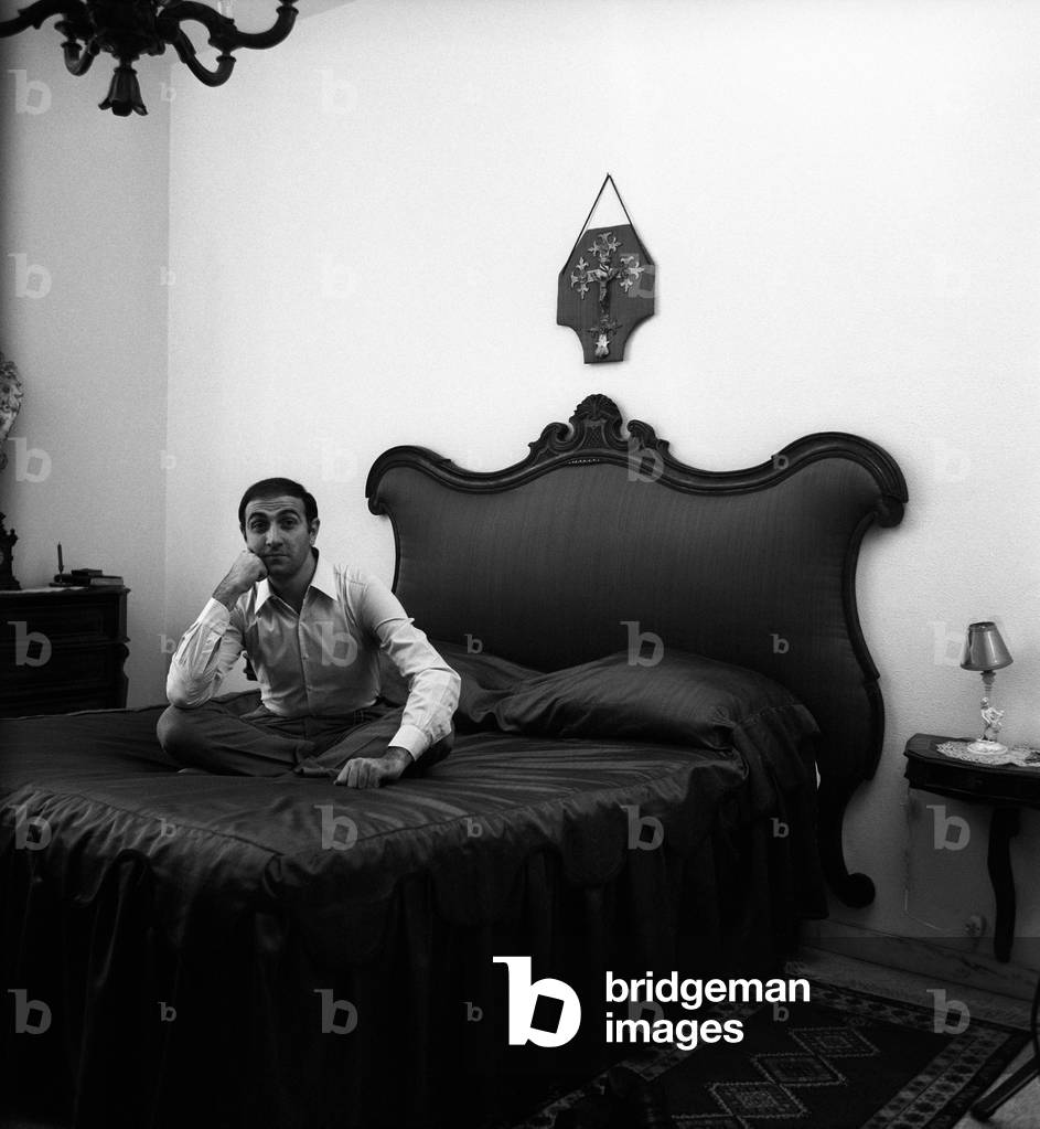 Pippo Baudo sitting on a bed