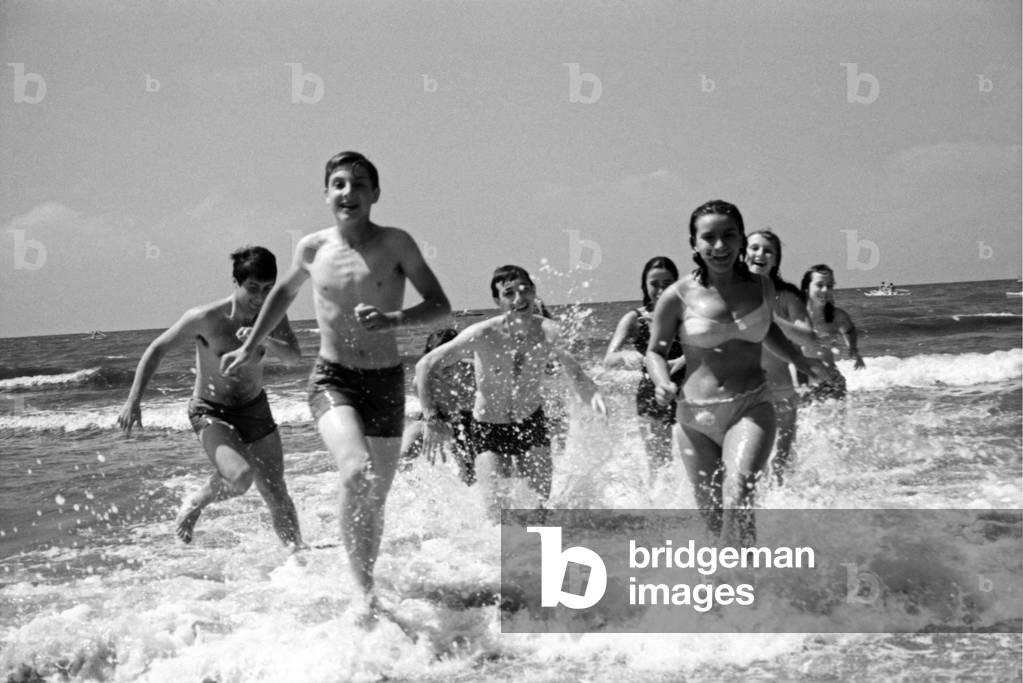 Boys and girls running amongst waves in Forte dei Marmi, Forte dei Marmi, Italy