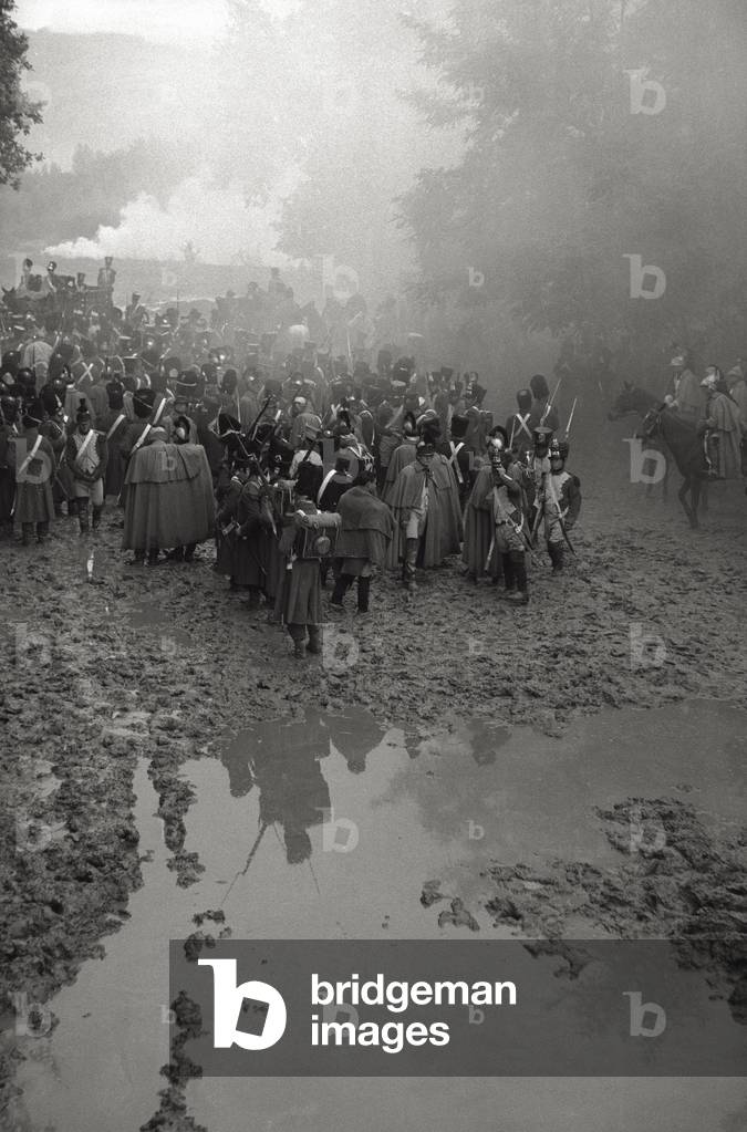 Actors and extras wearing stage costumes stride by foot, in a scene from King Vidor's 'War and Peace', 1955 (b/w photo)