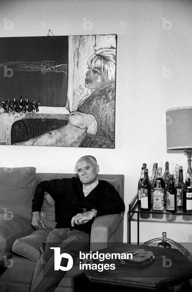 Alberto Moravia sitting on a sofa, Italy, 1960
