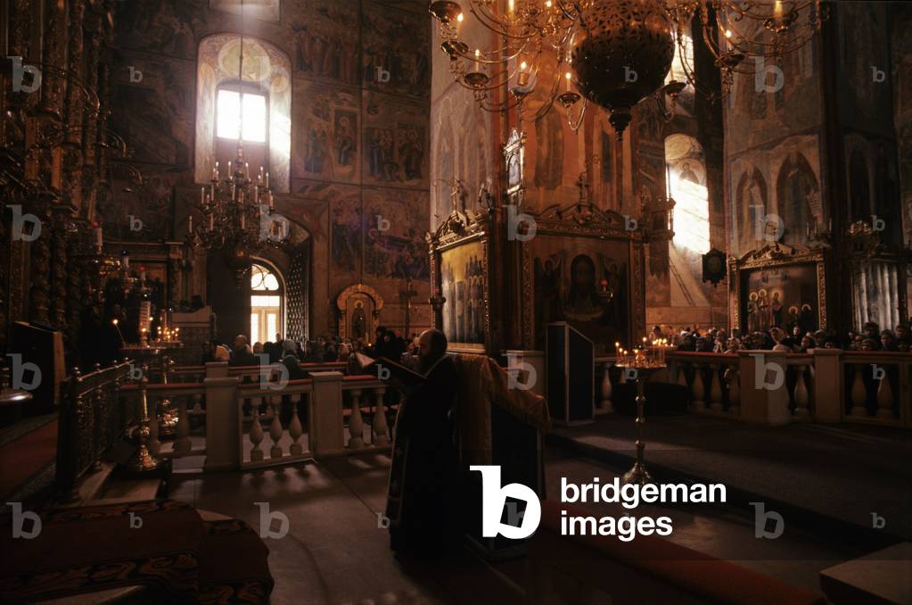 An orthodox priest sings to the many worshipers present within the Dormition Cathedral of Zagorsk, Zagorsk, Russian Federation