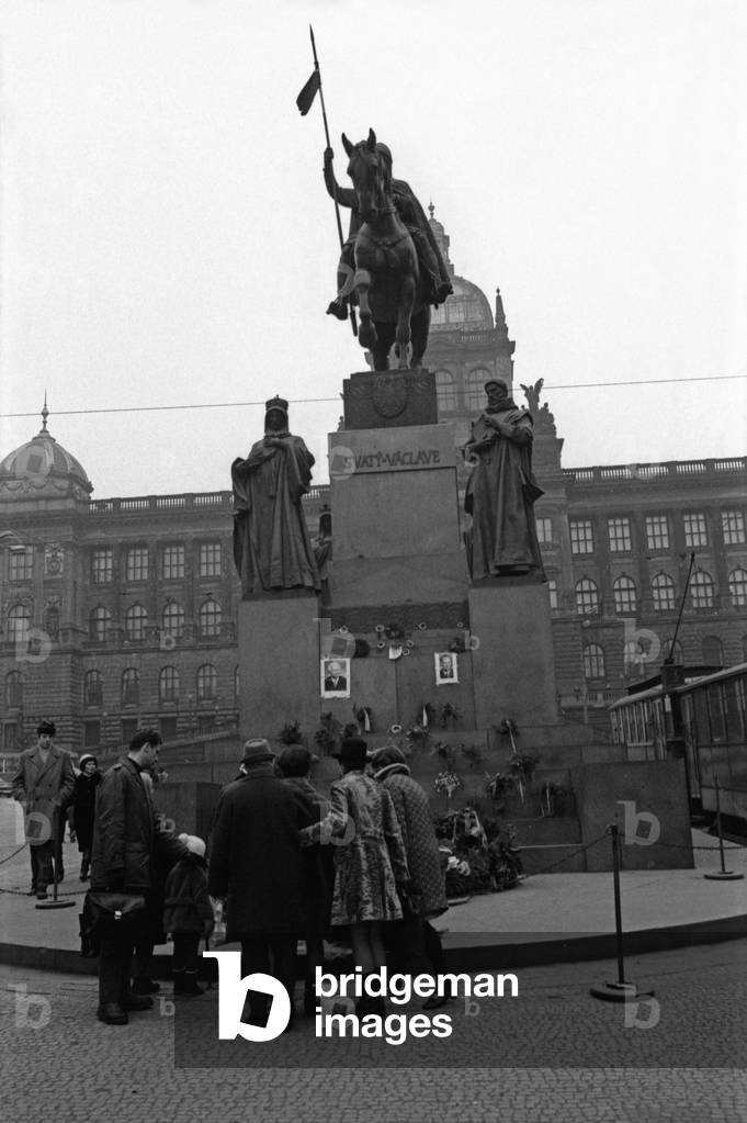 Some people looking at some memorial garlands at the foot of the equestrian statue of Saint Wenceslas on Wenceslas Square, Prague, Czech Republic, December 1968 (b/w photo)