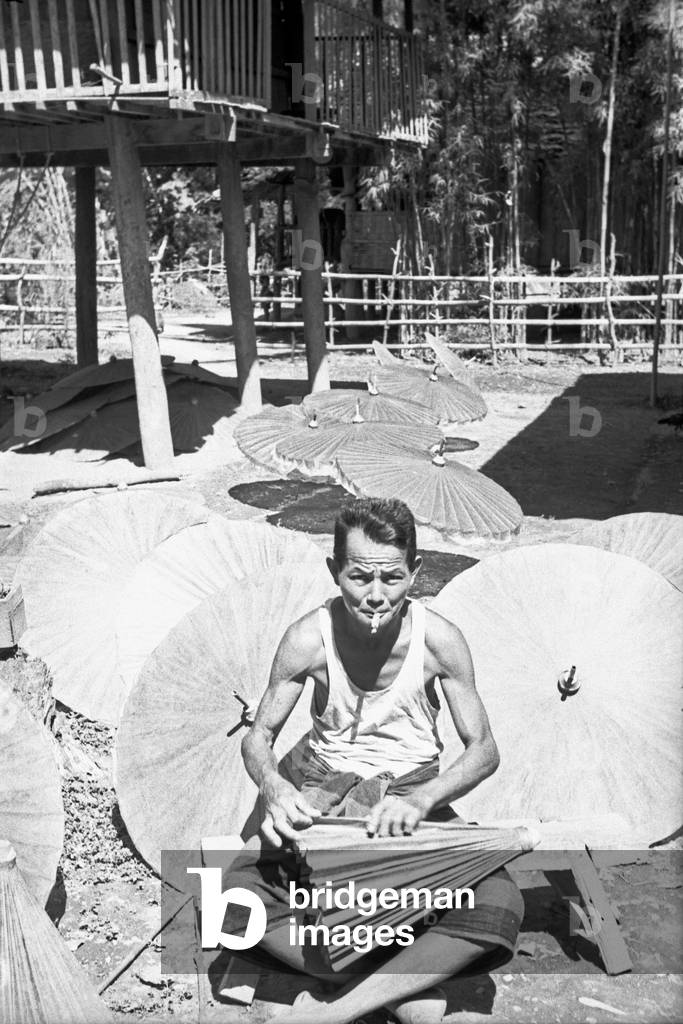An umbrella maker and seller making a new one, Bangkok, 1961 (b/w photo)
