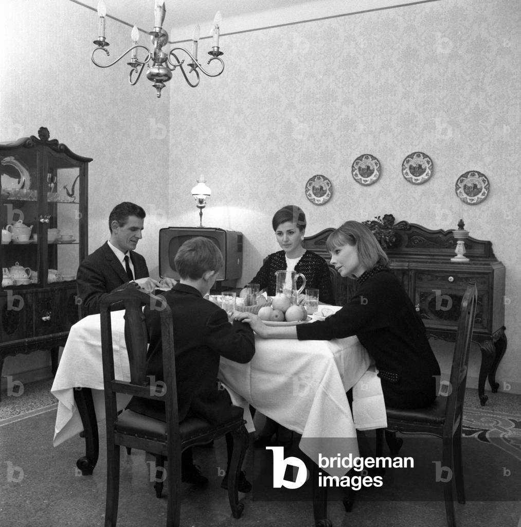A foreigner baby sitter eating with an Italian family, Italy, 1960s