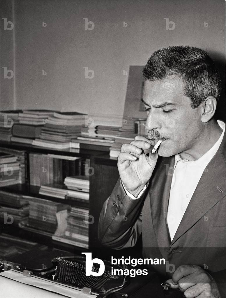 Elio Vittorini smoking in front of his typewriter, Italy, 1961 (b/w photo)