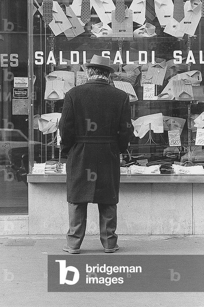 Man watching a shirt shop displaying goods on sale, Milan, January 1973 (photo)