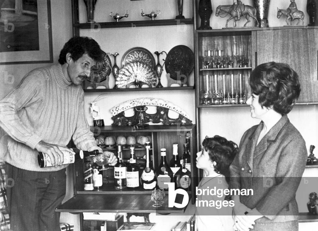 Ciccio Ingrassia pours a drink at the mobile bar, under the eyes of his son Giampiero and his wife Rosaria Calì, Italy