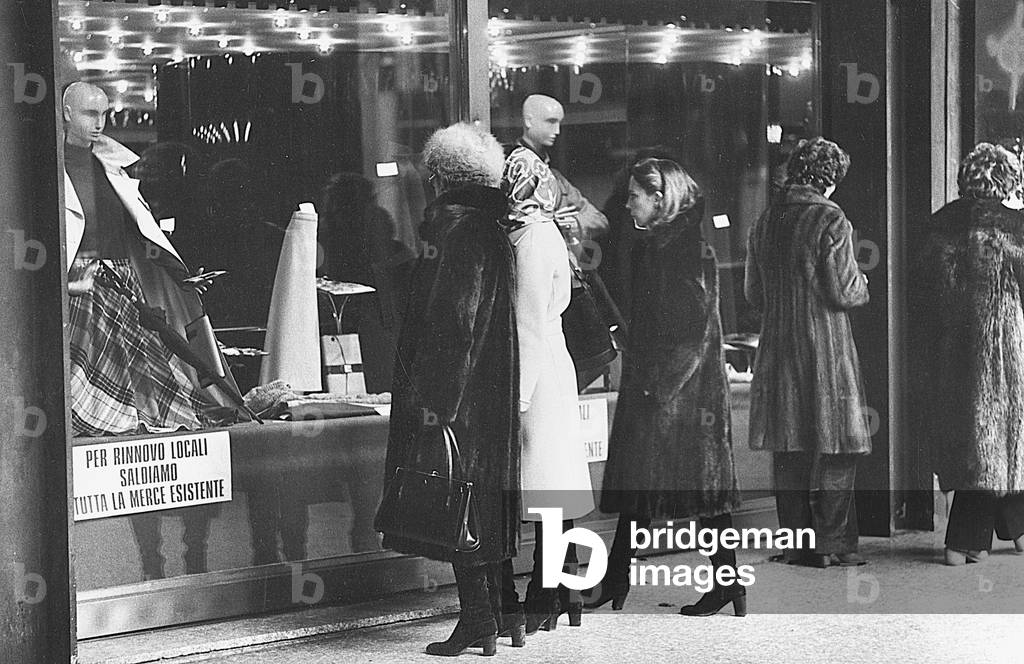Women watching the window of a shop displaying goods on clearance sale, Milan, 1979 (photo)