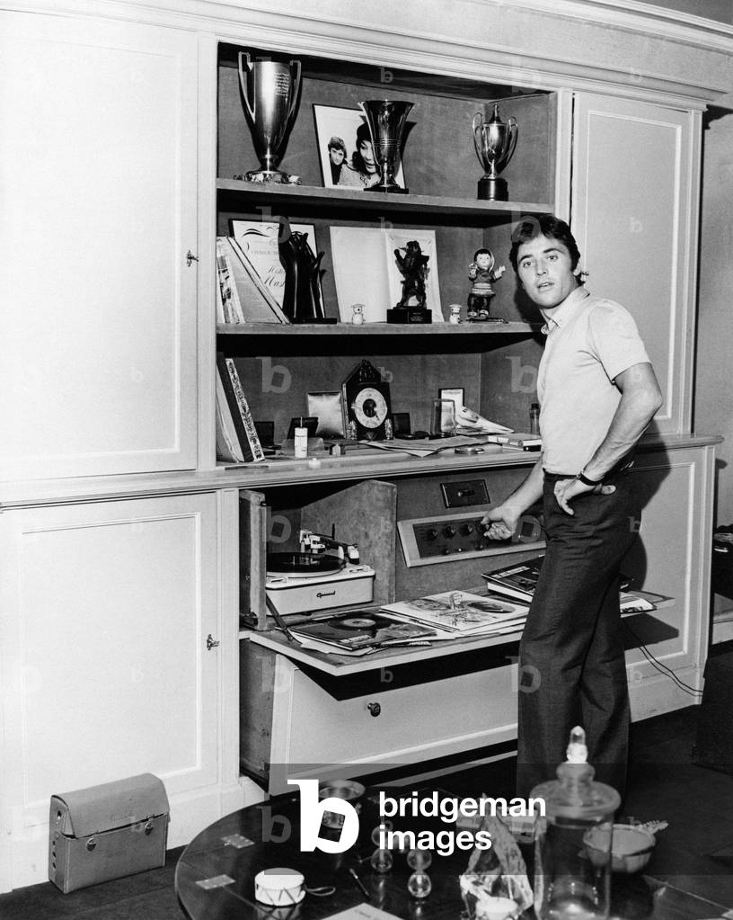 Sacha Distel adjusting the volume of a stereo system, Paris, France