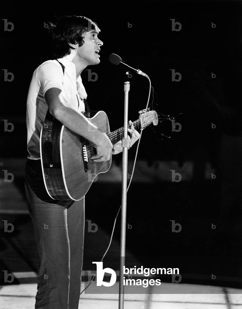 Gianni Morandi singing with a guitar