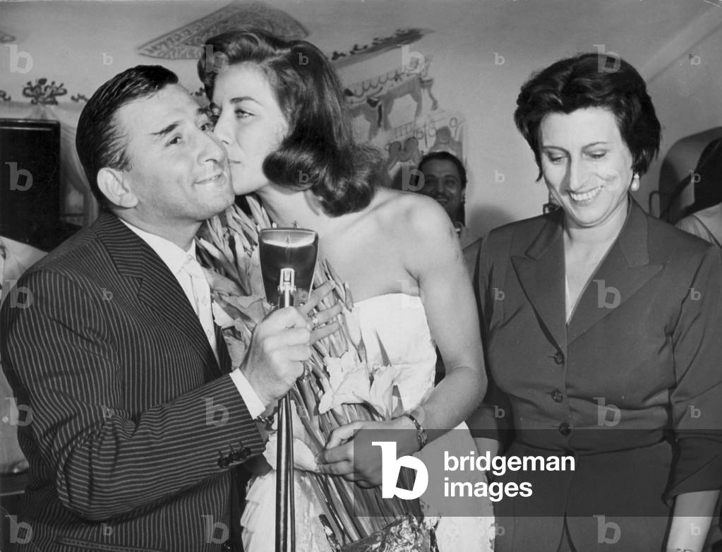 Renato Rascel is being kissed by Lise Bourdin, who is next to Anna Magnani, Italy
