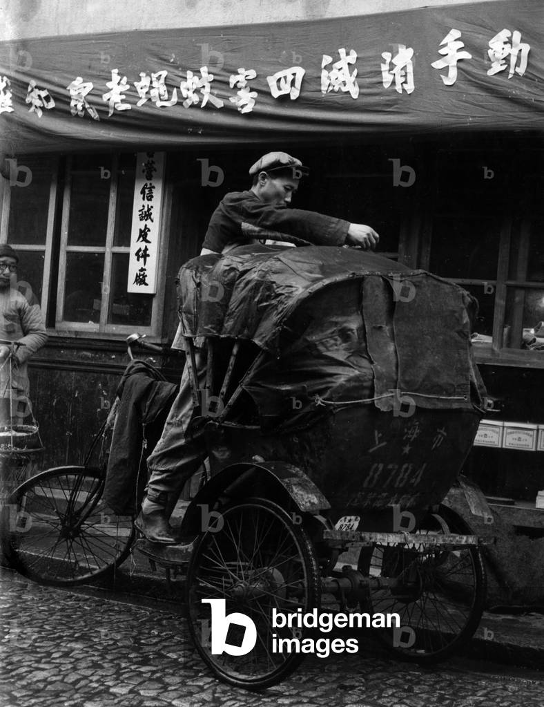 A 'coolie' mending the roof of his rickshaw