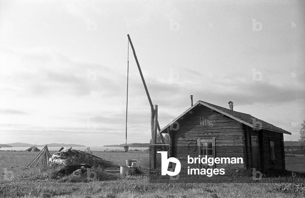 A solitary typical Finnish wooden house built in the middle of a field, Finland, 1960s (b/w photo)