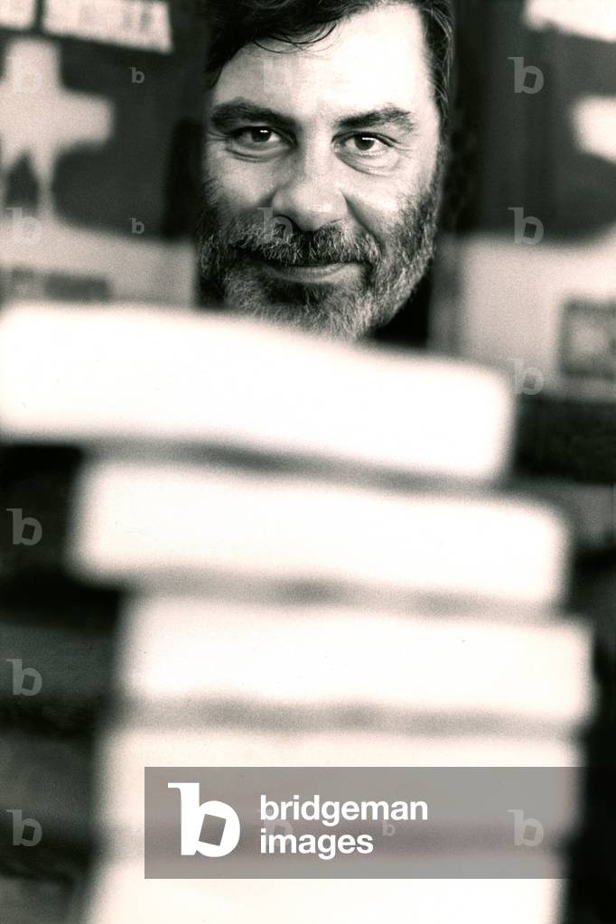 Portrait of Piero Soria behind a pile of books