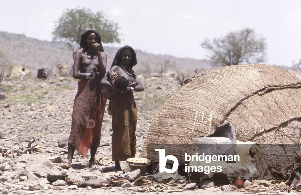Two women with a child in Danakil in front of their hut