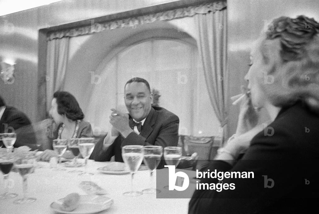 Richard Wright sitting at the table and smoking a cigarette