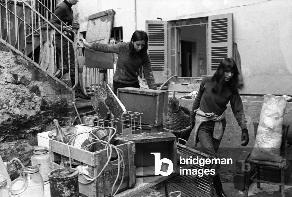Two girls carrying a flask after a flood in the district of Biella, Italy, 1968 (b/w photo)