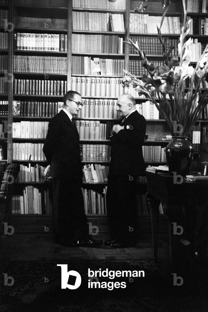 Two men talking in front of a bookcase, Milan, Italy, 1957