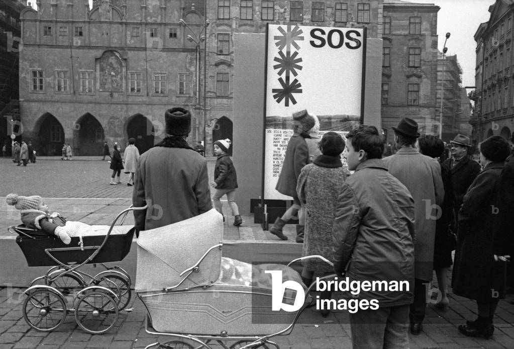 Some people walking on Old Town Square beside a Christmas Tree from the Bohemian forests, Prague, Czech Republic, December 1968 (b/w photo)