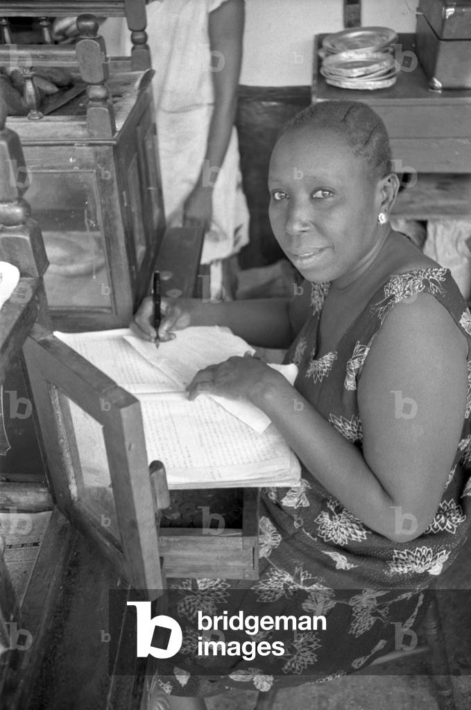 African woman writing, Zanzibar, October 1958 (b/w photo)