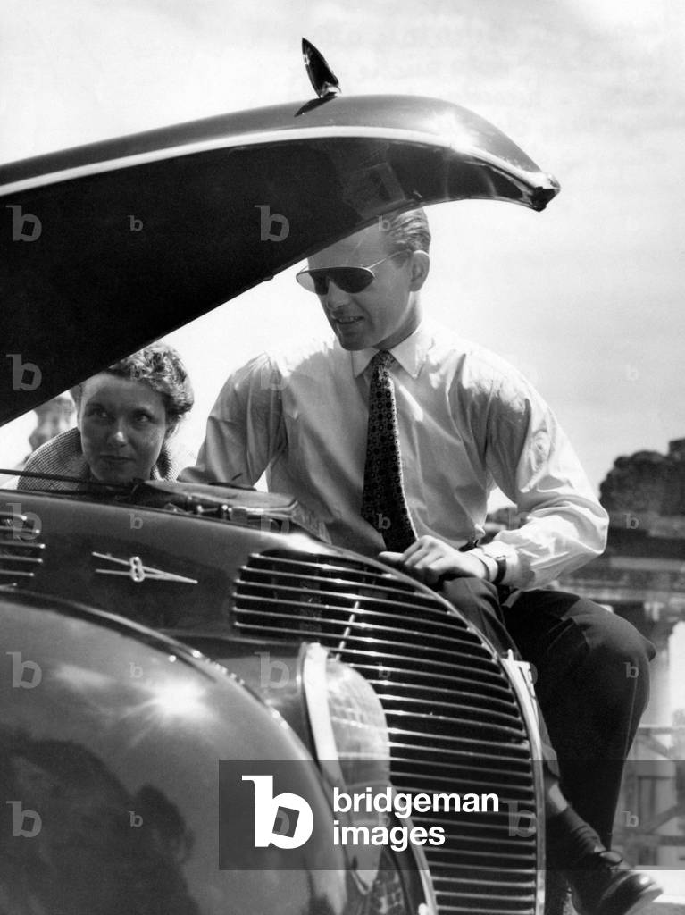 Jacques Sernas in front of a car with an open hood