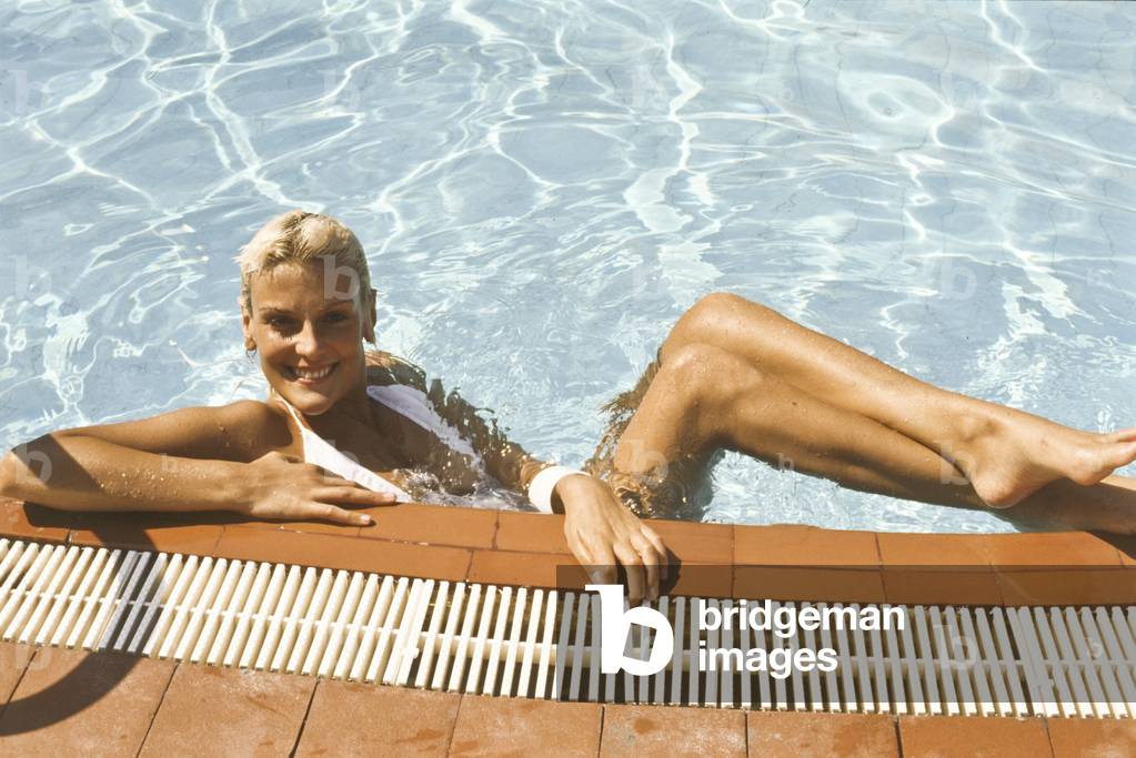 Donatella Rettore leaning at the edge of a swimming pool, Italy