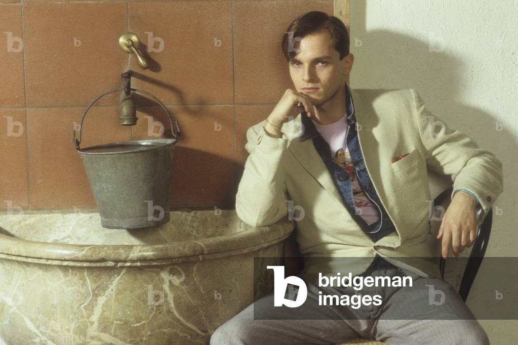 Miguel Bosé sitting thoughtful beside a fountain, Italy
