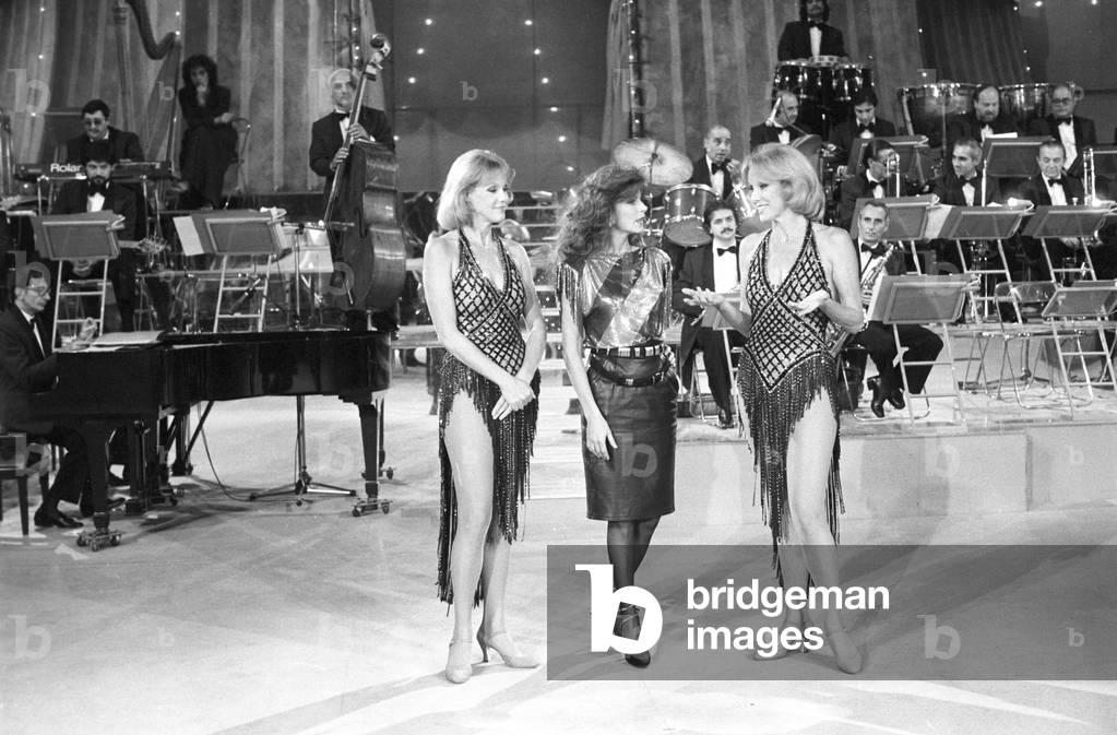 The twin sisters and artistic duo Alice and Ellen Kessler with Italian singer Milva, Italy, 1983 (b/w photo)