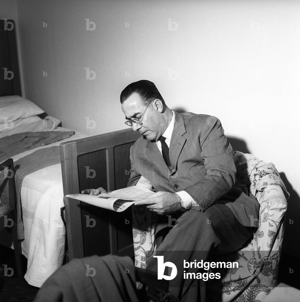 Alfredo Panicucci reading a newspaper seated on an armchair