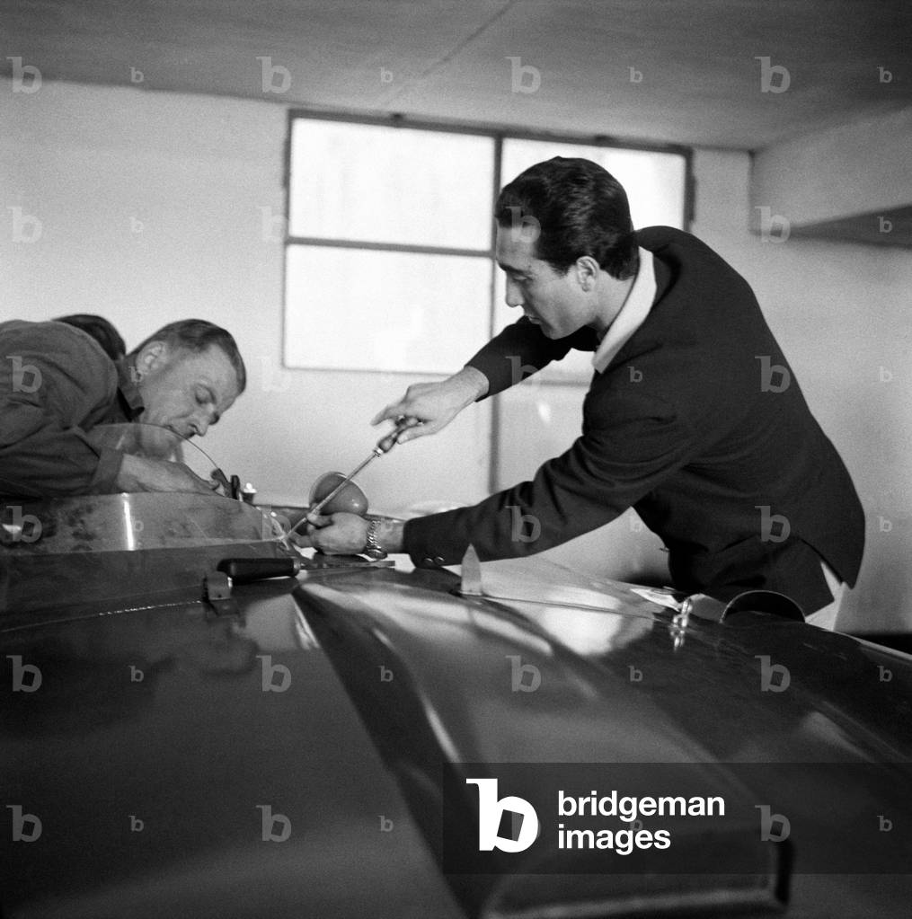 Eugenio Castellotti screwing a bolt of his Ferrari, Italy