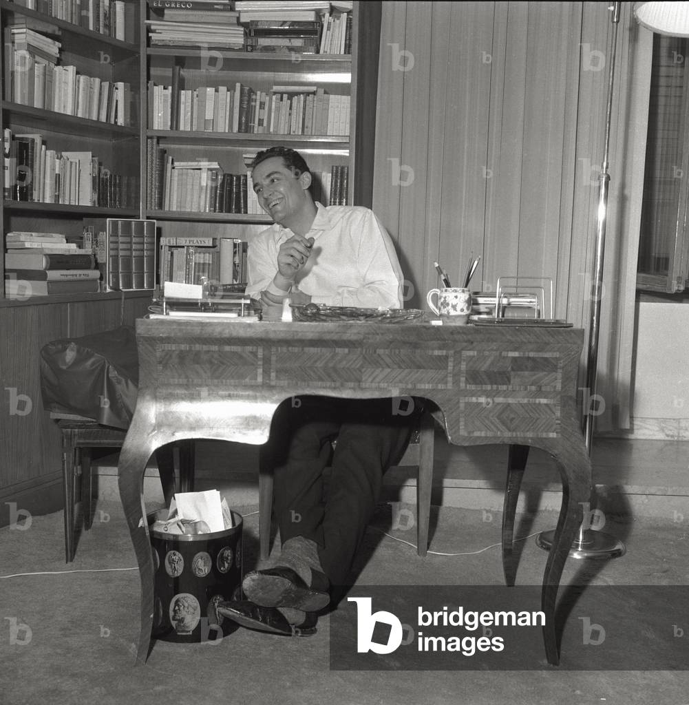 Vittorio Gassman sitting at the writing desk of his apartment, 1959 (b/w photo)