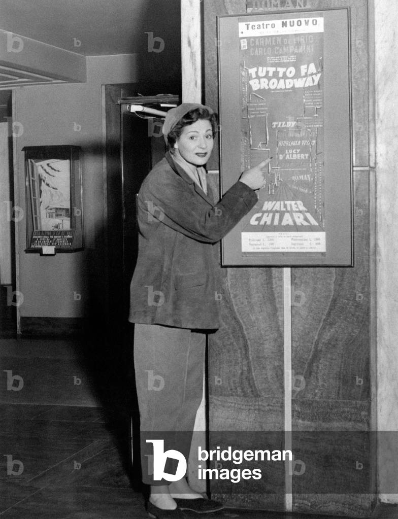 Lucy D'Albert pointing the poster of Tutto fa Broadway
