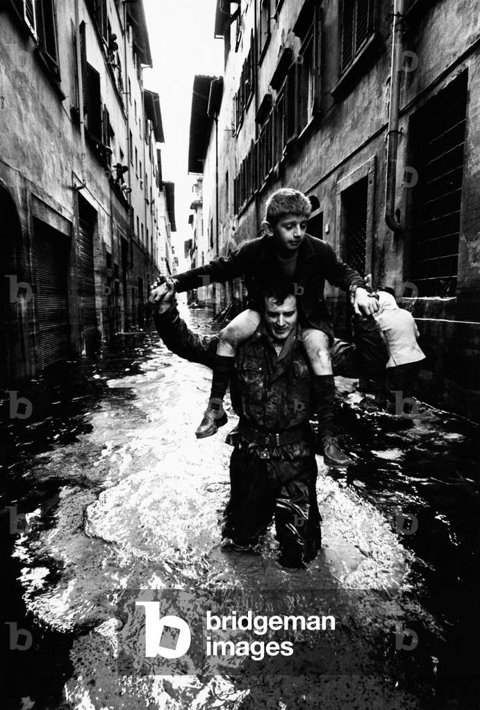 A soldier rescues a boy a flooded street