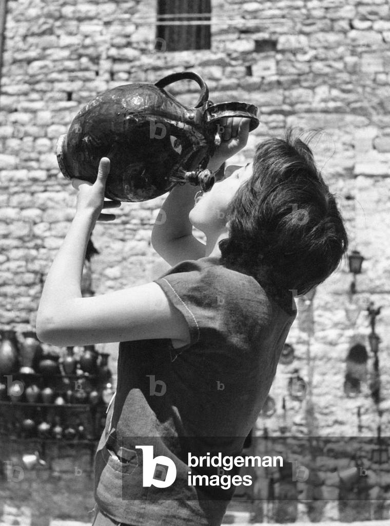 A girl drinks from an amphora, Italy, 1955 (b/w photo)