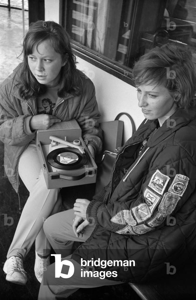 Two girls listening to some music from a portable record player, Finland, 1960s (b/w photo)