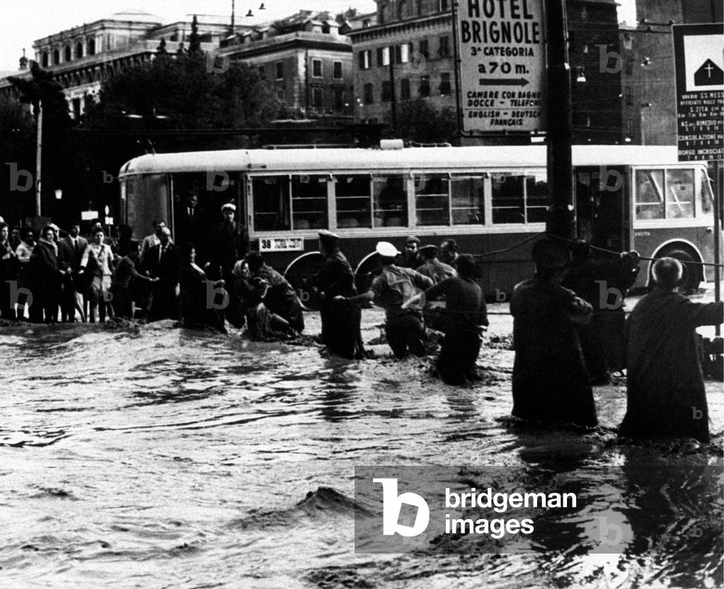 People crossing a flooded street by keeping theirselves clinged by a rope, Genoa, Italy