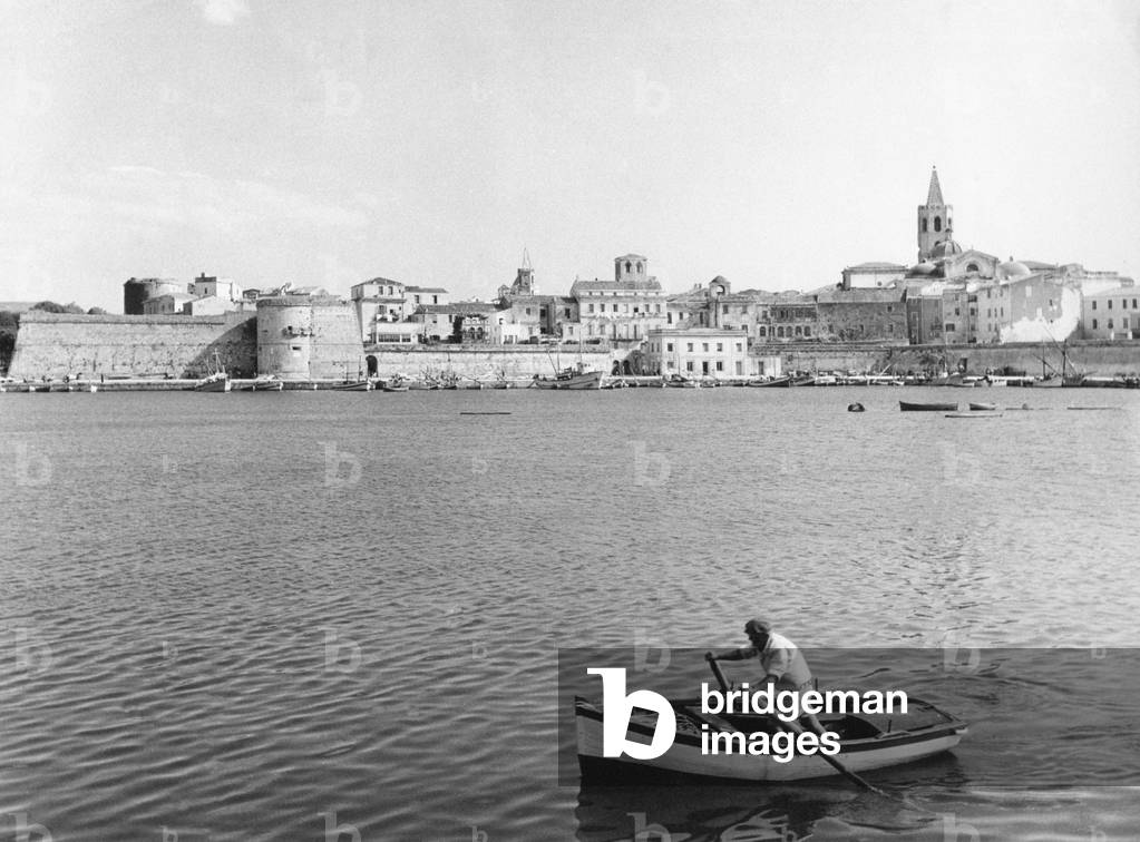 A man on a rowing boat at the harbour of Alghero, Alghero, Italy