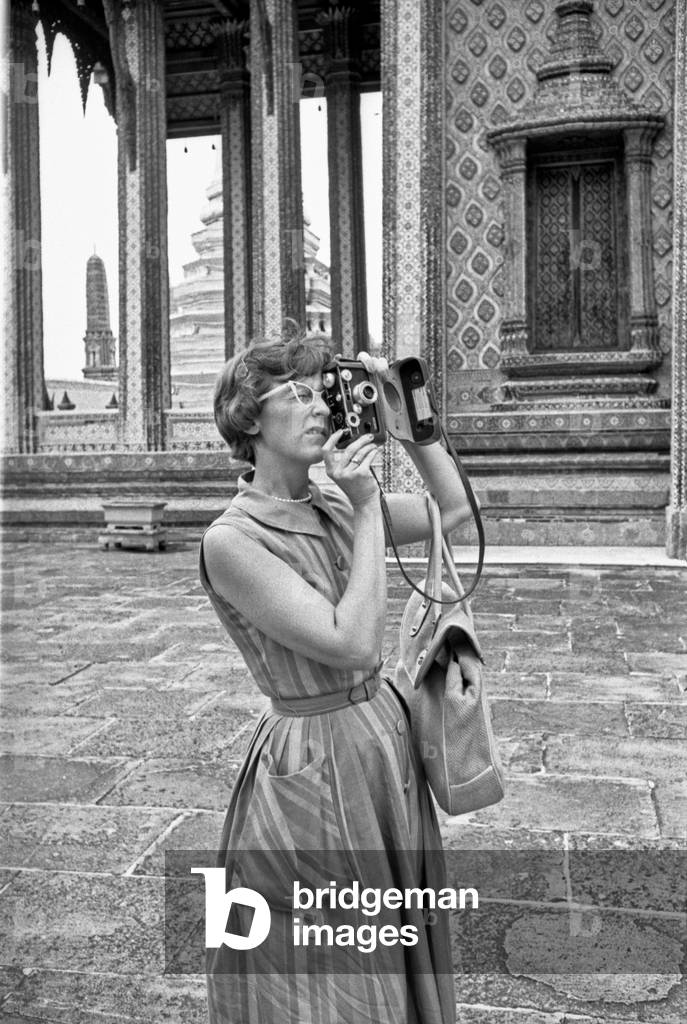A tourist taking pictures at Wat Phra Kaew Buddhist Temple, Bangkok, 1961 (b/w photo)