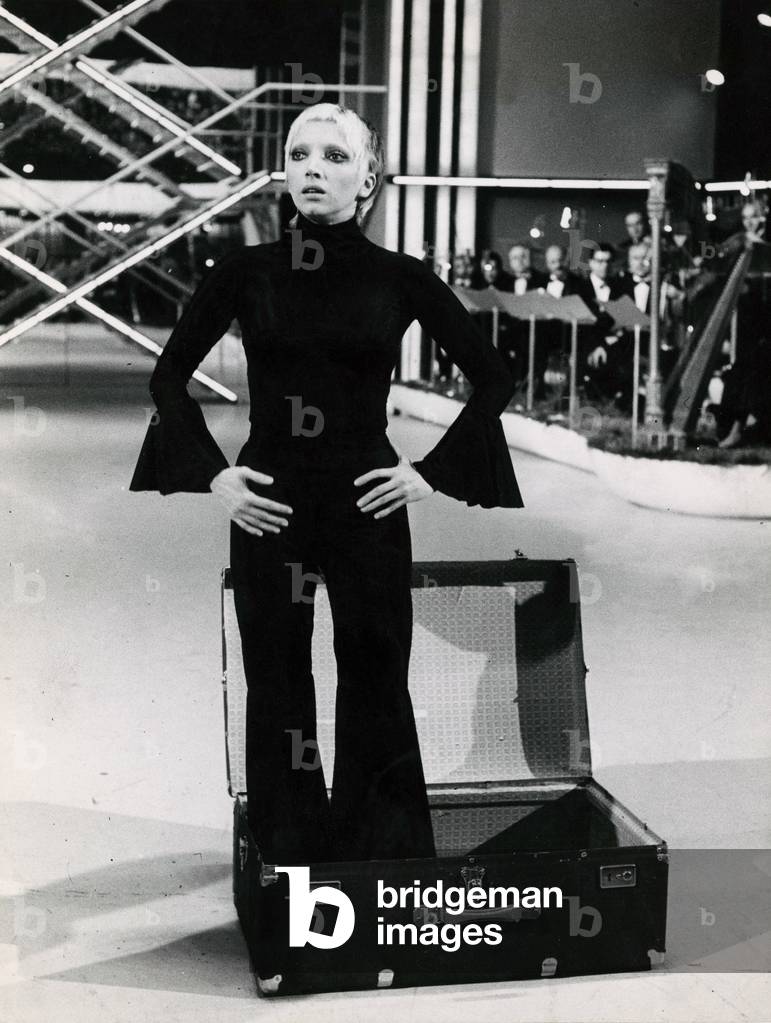 Mariangela Melato standing in a suitcase