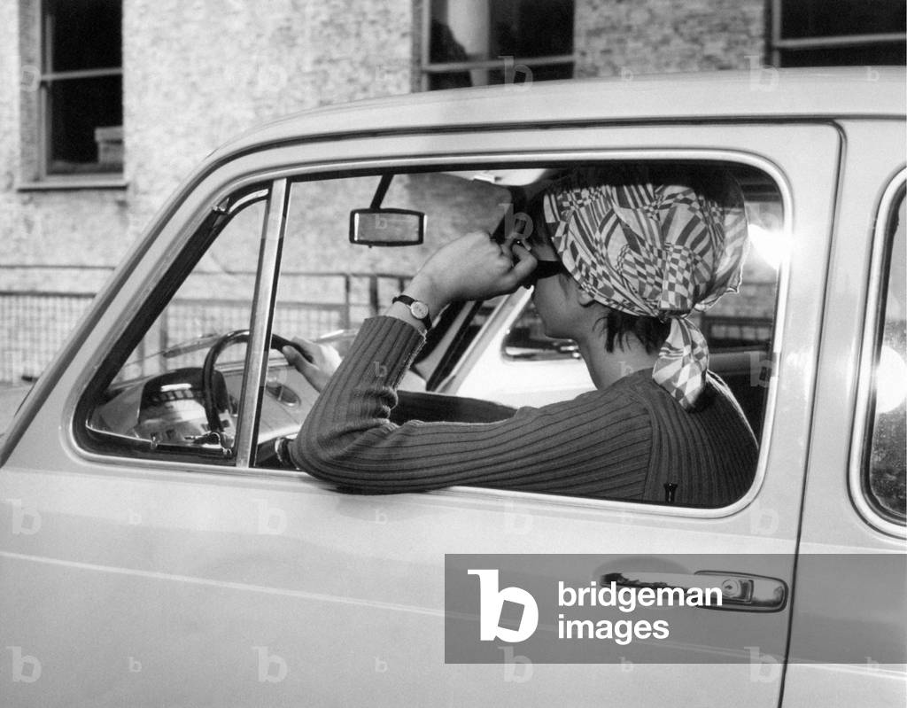 A girl driving a car, leaning her arm out of the car window, Milan, Italy