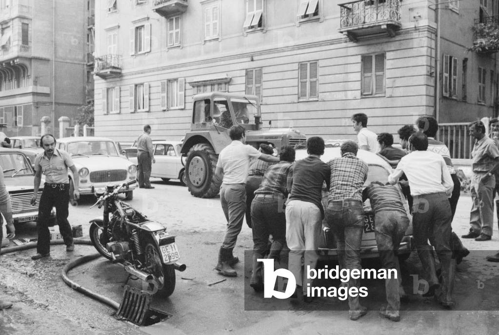 People pushing a car, Italy, 1970 (b/w photo)