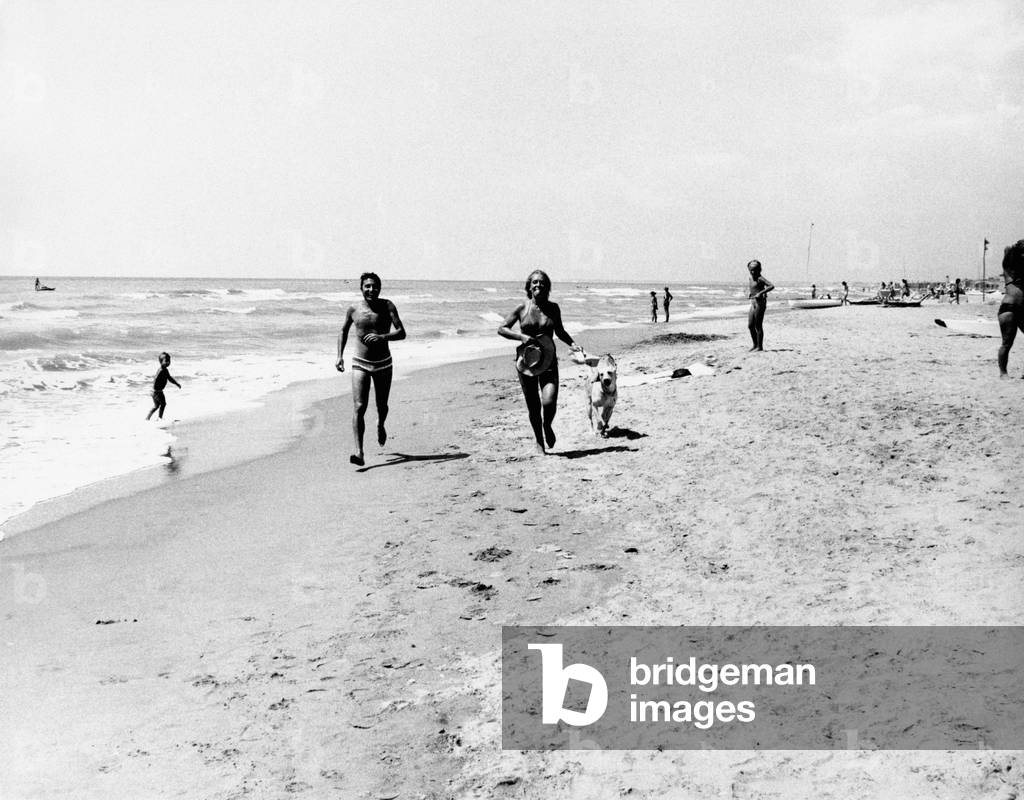 Piano Caruso and his wife Marilisa Ferzetti are running on the beach with their dog