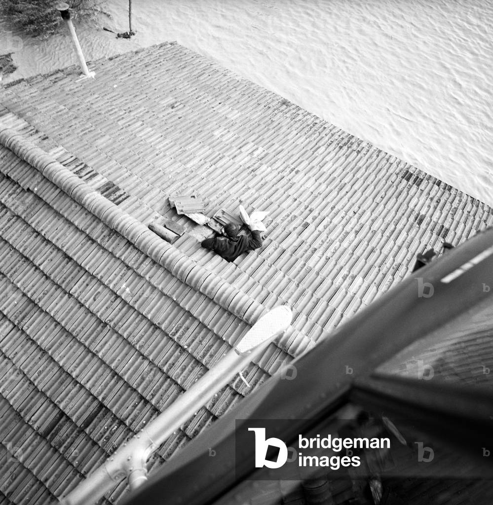 A man on the roof of his house during Florence flood (b/w photo)