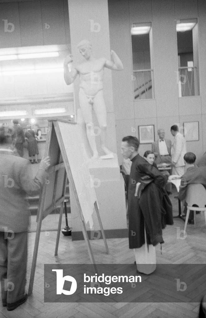 A man reading a poster in front of a sculpture in Geneve, Geneva, Switzerland