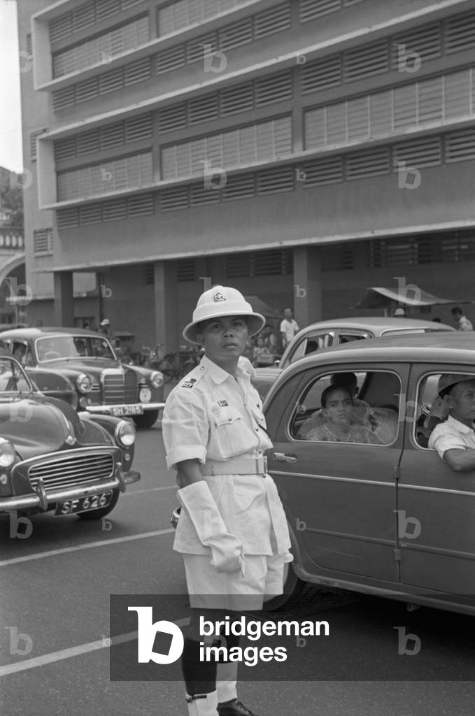 Traffic policeman directing traffic in a street of Singapore, Singapore, 1962 (b/w photo)