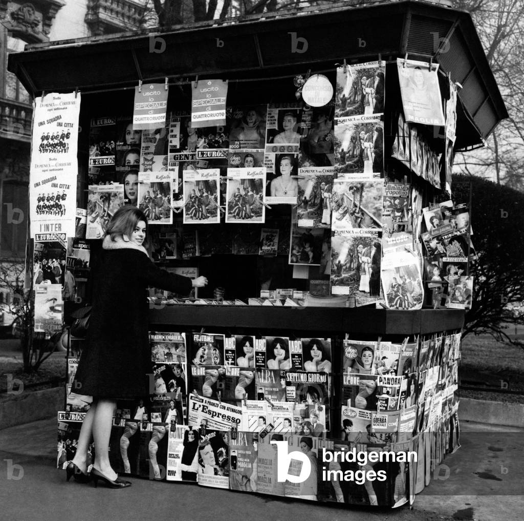 A girl buys a magazine at a newsagent